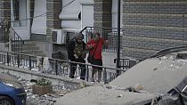 A police officer helps an injured man evacuate to an ambulance from a multi-story apartment building which was damaged in a relentless wave of bombardments targeting in Kyiv