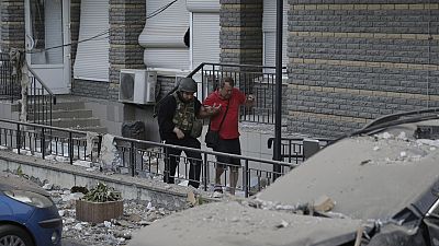 A police officer helps an injured man evacuate to an ambulance from a multi-story apartment building which was damaged in a relentless wave of bombardments targeting in Kyiv