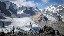 People stand in front of the Pers and Morteratsch glaciers in Pontresina, Switzerland. August 2022.
