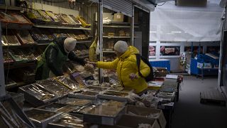 Une femme achète à un vendeur sur un marché de Kiev, en Ukraine, lundi 30 janvier 2023.