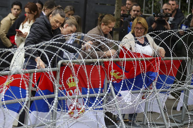 Women attach Serbian flags to a fence in front of the city hall during a protest in the town of Zvecan, northern Kosovo, Wednesday, May 31, 2023
