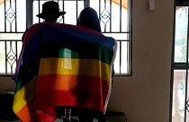 زوجان أوغنديان مثليان يغطيان أنفسهما بعلم الفخر لالتقاط صورة في أوغندا، 25 مارس 2023.