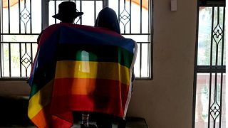 زوجان أوغنديان مثليان يغطيان أنفسهما بعلم الفخر لالتقاط صورة في أوغندا، 25 مارس 2023.