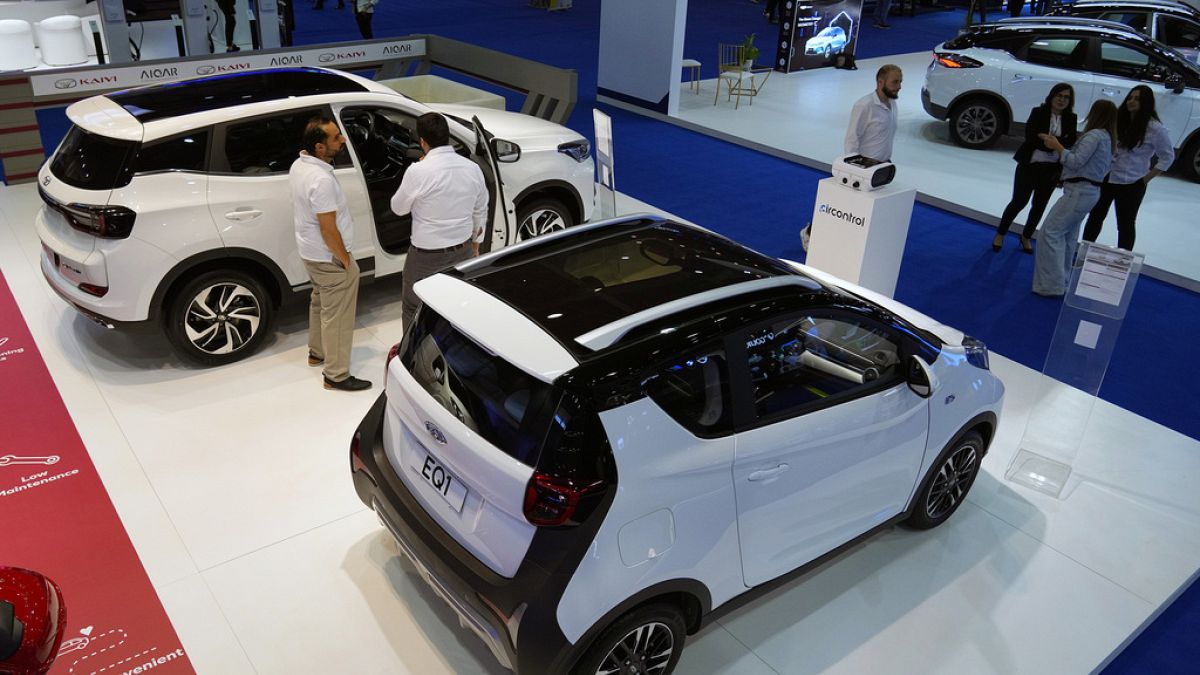 Visitors stand next to the new electric Chery EQ1 cars which display at the e-Motor show in Beirut, Lebanon.