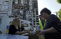Des habitants reçoivent des repas gratuits sur le fond de leur immeuble endommagé à Kharkiv, en Ukraine, 02/06/2023