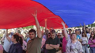People hold up a giant Serbian flag during a protest in Belgrade, Serbia, Saturday, June 3, 2023