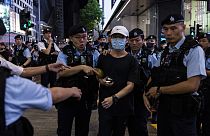 Egy hongkongi fiatal rendőrök gyűrűjében, miután telefon-lámpájának bekapcsolásával emlékezett az áldozatokra