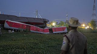 Αστυνομικός μπροστά από εκτροχιασμένο βαγόνι τρένου μετά το πολύνεκρο σιδηροδρομικό δυστύχημα στην Ινδία
