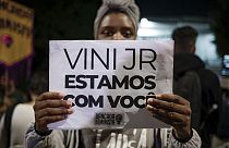 A woman holds a sign with a message that reads in Portuguese; "Vini, we are with you," during a protest against the racism suffered by Brazilian soccer star Vinicius Junior.