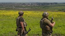 Zwei ukrainische Soldaten mit der Stadt Bachmut im Hintergrund