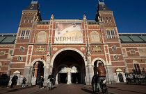 Cyclists pass under the Vermeer exhibit sign at Amsterdam's Rijksmuseum, Monday, Feb. 6, 2023.