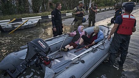 Rescue workers attempt to tow boats carrying residents being evacuated from a flooded neighborhood in Kherson, Ukraine, Tuesday, June 6, 2023. 