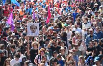 متظاهرين يرفعون لافتة ساخرة للرئيس الفرنسي إيمانويل ماكرون