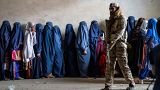 عنصر من طالبان يحرس نساء ينتظرن استلام معونات غذائية في كابول 23/05/2023