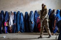 عنصر من طالبان يحرس نساء ينتظرن استلام معونات غذائية في كابول 23/05/2023