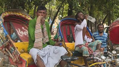 عمال يحاولون وقاية أنفسهم من موجة الحر في دكا