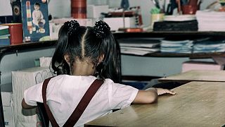 طفلة جالسة وظهرها للكاميرا في صف دراسي