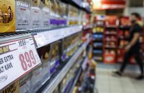 Bevásárló egy budapesti CBA-üzletben, az előtérben egy akciós árcédulával