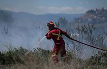 یک آتش نشان، دوشنبه، ۵ ژوئن ۲۰۲۳، آب را روی یک آتش سوزی چمن در زمینی در پشت یک ملک مسکونی در کاملوپس، بریتیش کلمبیا هدایت می‌کند.
