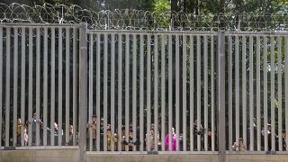 Migrants at a border fence.