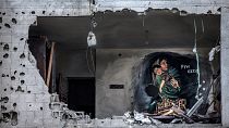 A mural is seen through a hole in a wall in a house heavily damaged in an Israeli air strike