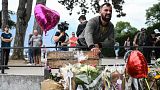 A man reacts in front of flowers and candles for the victims of a stabbing attack that occured the day before in the 'Jardins de l'Europe' parc in Annecy, France.
