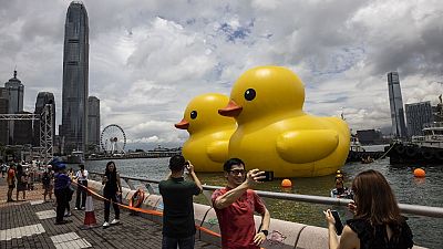 People take photos of two large inflatable yellow ducks called "Double Duck" by Dutch artist Florentijn Hofman in Victoria Harbour in Hong Kong on June 9, 2023.