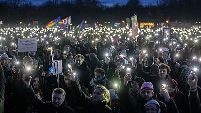 People hold up their cell phones as they protest against the AfD party and right-wing extremism in front of the Reichstag building in Berlin, Germany, Sunday, Jan. 21, 2024. 