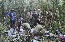 In this photo released by Colombia's Armed Forces Press Office, soldiers and Indigenous men tend to the four Indigenous brothers who were missing after a deadly plane crash.
