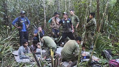 In this photo released by Colombia's Armed Forces Press Office, soldiers and Indigenous men tend to the four Indigenous brothers who were missing after a deadly plane crash.