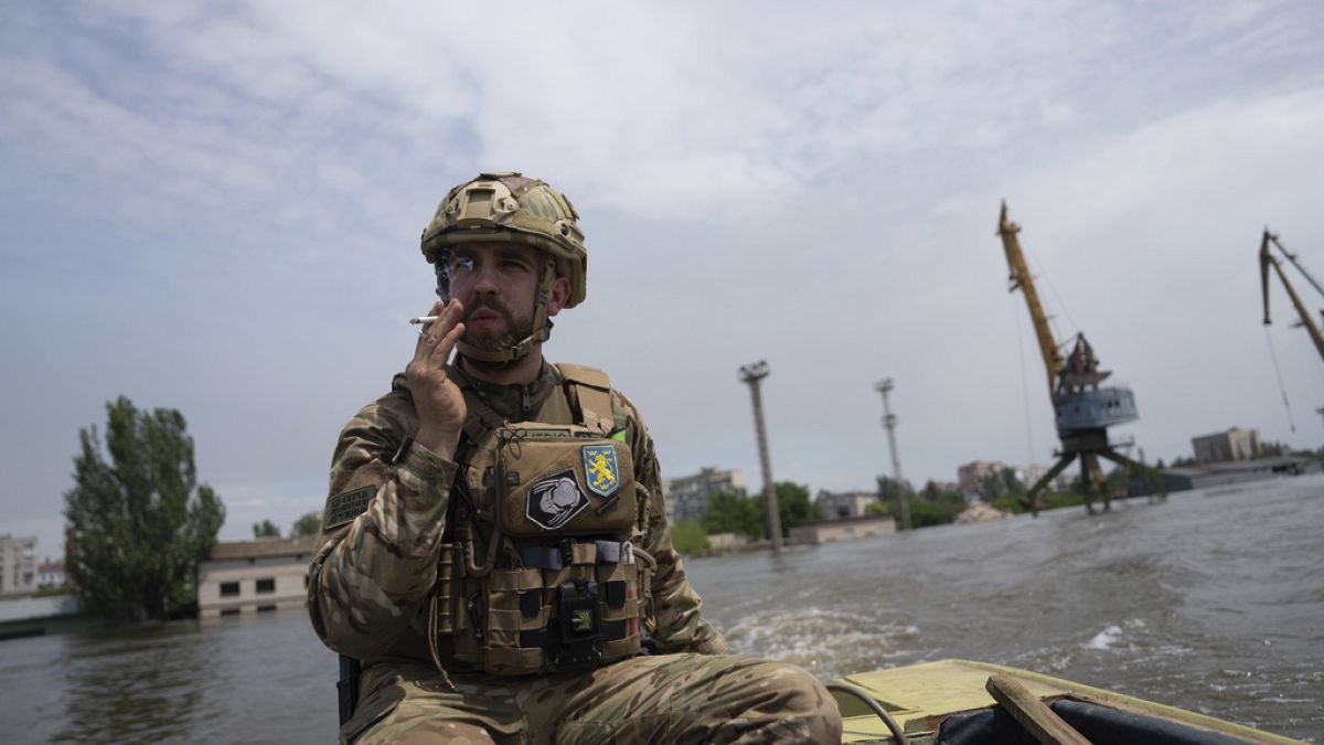 A Ukrainian serviceman steers a boat in a flooded neighborhood in Kherson, Ukraine, Thursday, June 8, 2023.