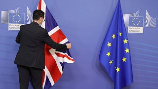 A member of protocol adjusts the EU and Union flag prior  at EU headquarters in Brussels, Feb. 21, 2022.