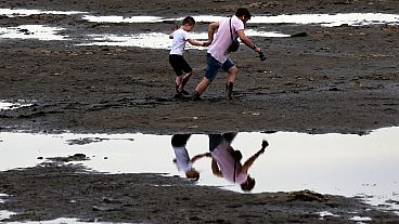 Moradores de Zaporíjia atravessam o rio Dnipro transformado em lama