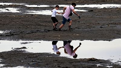 Vecinos de Zaporiyia caminan por el lodo del río Dnipro, el 10 de junio de 2023.
