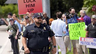 A police officer helps with traffic control as protesters and supporters wait for Trump to arrive at Trump National Doral resort in Doral, Fla., Monday, June 12, 2023.