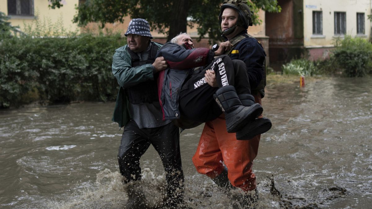 Emergency teams help an evacuee who had came under fire from Russian forces while trying to flee by boat from the Russian-occupied east bank of a flooded Dnipro River
