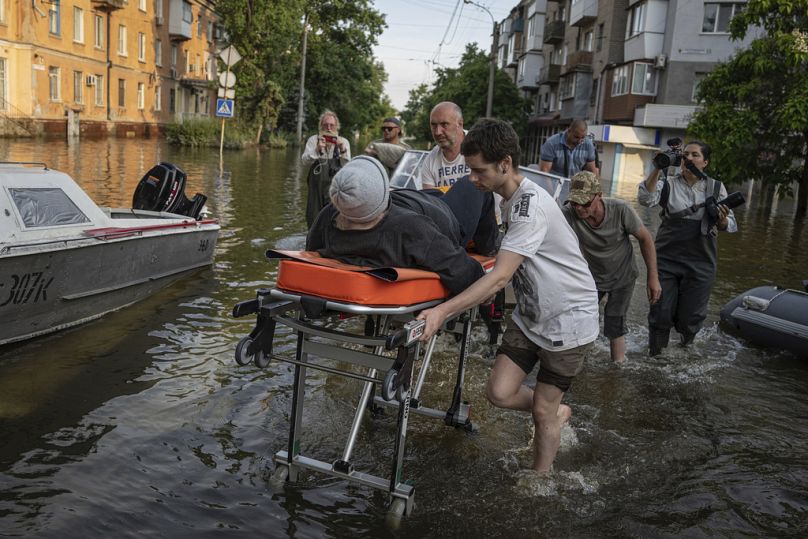 Volunteers haul a woman on a stretcher as she been evacuated from a flooded neighborhood of the left bank Dnipro river, in Kherson, June 2023