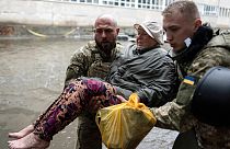 Ukrainische Soldaten helfen einer Frau, die durch russischen Beschuss verletzt wurde