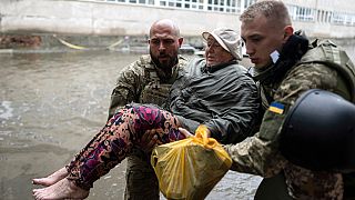 Des sauveteurs ukrainiens aident une femme blessée par les frappes russes à Kherson, 11 juin 2023.
