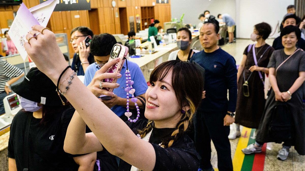 A Japanese fan takes a photo of stationary as she queues up to buy a special commemorative stamp series of K-pop megastars BTS,