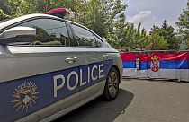Rendőrautó Koszovóban szerb zászló előtt - képünk illusztráció