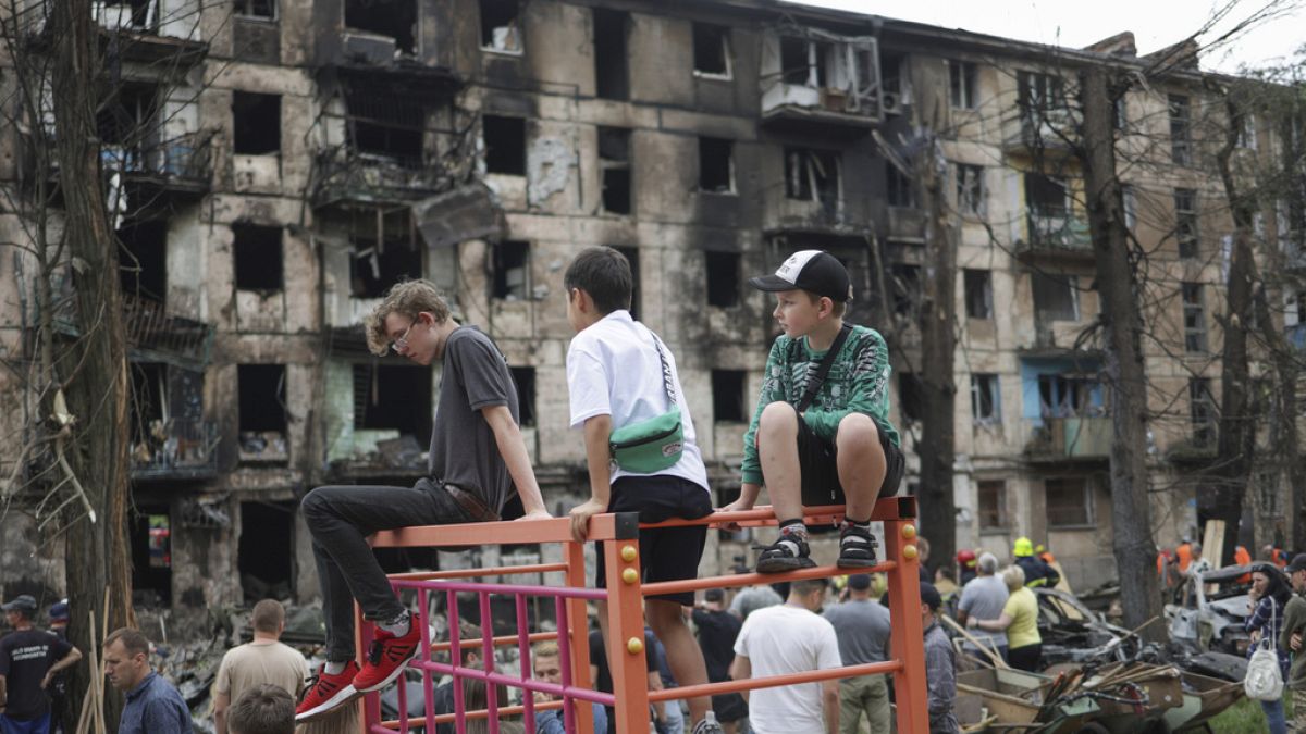 Bambini guardano la scena dell'ultimo attacco missilistico russo che ha danneggiato un edificio di appartamenti a più piani a Kryvyi Rih, in Ucraina, martedì 13 giugno 2023.