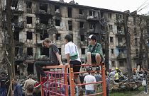 Children look at the scene of the latest Russian rocket attack that damaged a multi-storey apartment building in Kryvyi Rih, Ukraine, Tuesday, June 13, 2023.