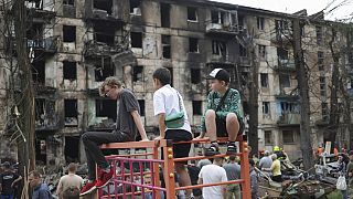 Bambini guardano la scena dell'ultimo attacco missilistico russo che ha danneggiato un edificio di appartamenti a più piani a Kryvyi Rih, in Ucraina, martedì 13 giugno 2023.