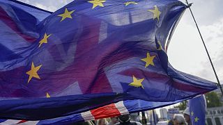A Union flag waves behind a European Union flag, outside the Houses of Parliament, in London, Oct. 19, 2022.