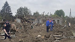 A Ukrainian police officer carries a wounded victim of the deadly morning Russian rocket attack amid debris of the ruined private houses in Kramatorsk,Ukraine, 14 June 2023