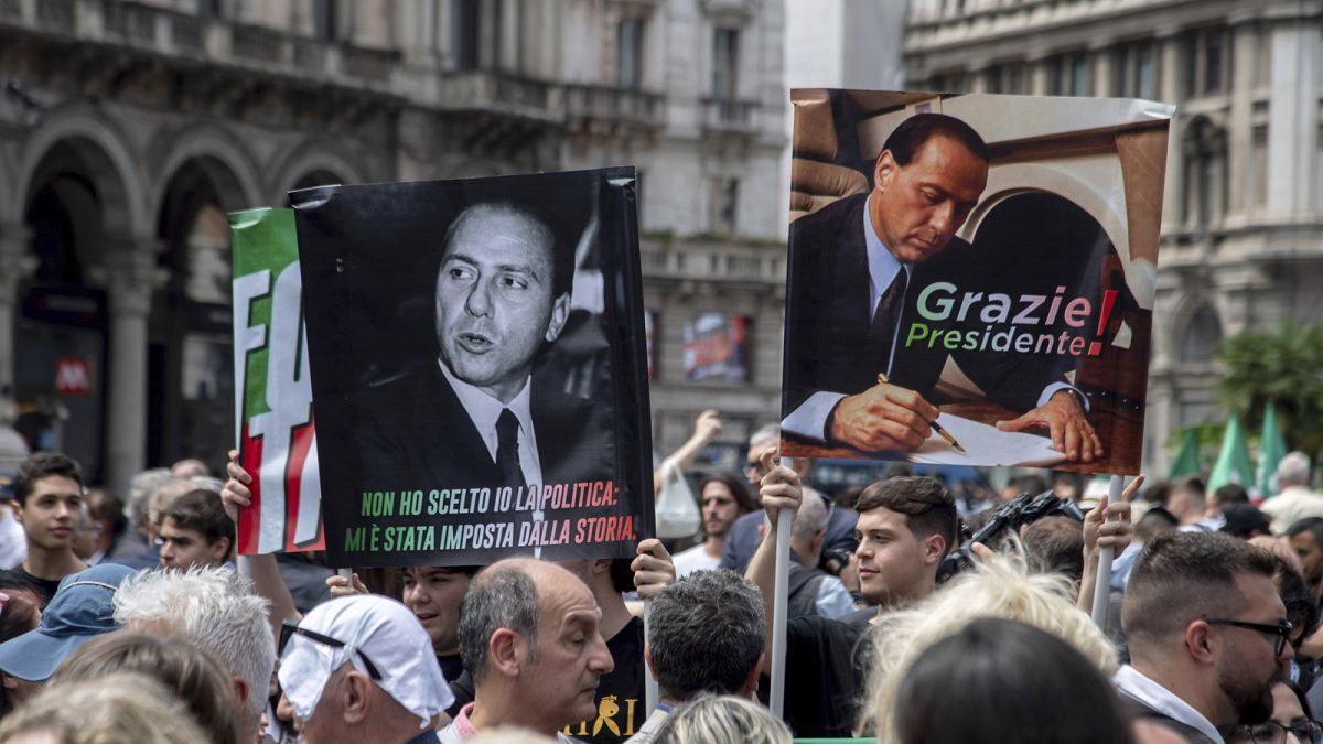 Mourners and supporters of Silvio Berlusconi hold placards outside of his state funeral in Milan Cathedral. Wednesday, 14 June 2023.