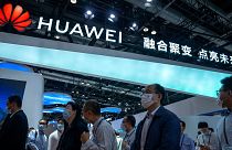 Visitors walk past a booth for Chinese technology firm Huawei at the PT Expo in Beijing, 2021