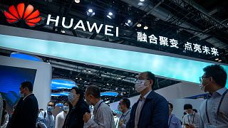 Visitors walk past a booth for Chinese technology firm Huawei at the PT Expo in Beijing, 2021