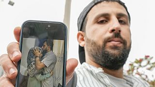 Kassem Abo Zeed holds up a phone displaying a photo of himself with his wife, Ezra, who is missing after a fishing boat carrying migrants sank off southern Greece.